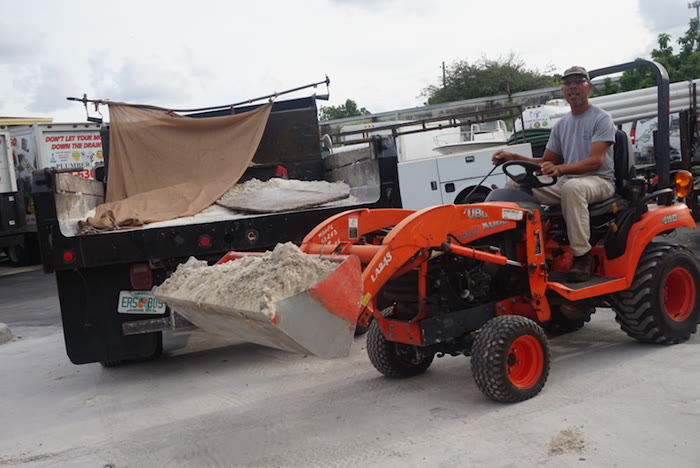 Plumber Mike's crew loading fill with a tractor beside a dump truck on a sewer connection job